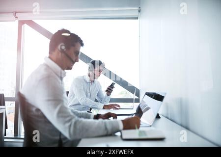 Callcenter, Laptop und Männer im Büro mit Kundendienst für technischen Support, Kommunikation oder Problemlösung. Beratung, CRM und Agenten mit Stockfoto