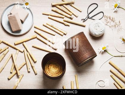 Blick von oben auf den Arbeitsplatz mit zwei alten leeren, rostigen Essenskannen, Bambuspfählen, luftgetrocknetem Ton, Schnur, Schere. Erstellen Sie ein DIY-Bug-Hotel für den Garten. Kinderbasteln Stockfoto