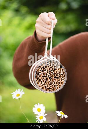 Handgefertigtes Insektenhotel in der Hand eines Mädchens, bereit zum Aufhängen im Sommergarten. Erstellen Sie ein DIY-Bug-Hotel für den Garten. Kinder basteln und helfen wilden Tieren Stockfoto