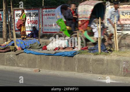 Ein Teenager aus einer obdachlosen Familie lernt am besten an einem sonnigen Wintermorgen, um ein Bett auf einem Straßenteiler zu bekommen. Das Foto stammt von Palashi Ar Stockfoto