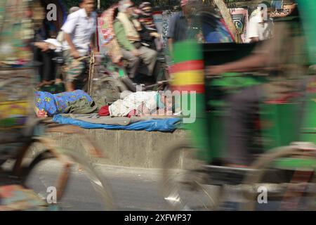 Ein Teenager aus einer obdachlosen Familie lernt am besten an einem sonnigen Wintermorgen, um ein Bett auf einem Straßenteiler zu bekommen. Das Foto stammt von Palashi Ar Stockfoto