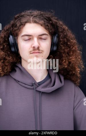 Junger Mann mit geschlossenen Augen, der Musik über Kopfhörer hört Stockfoto