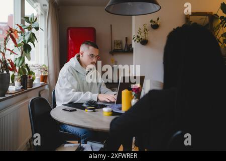 Junger männlicher Freiberufler, der am Laptop arbeitet und im Home Office sitzt Stockfoto