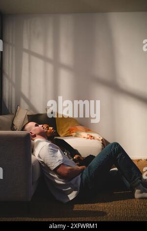 Seitenansicht eines jungen Paares, das sich zu Hause in der Nähe des Sofas liegend Stockfoto