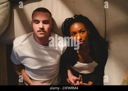Junge Frau, die Hand des Freundes hält, während sie sich zu Hause auf dem Sofa zurücklehnt Stockfoto