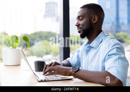 Arbeit am Laptop, Mann Tippen und Kaffeetrinken im modernen Büro Stockfoto