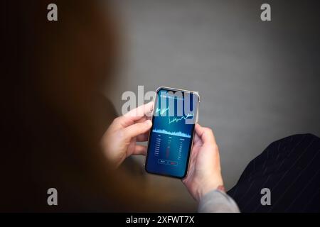 Zugeschnittenes Bild einer Geschäftsfrau, die Diagramme auf dem Mobiltelefon analysiert Stockfoto
