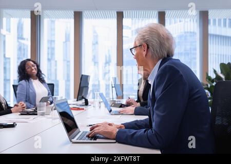 Leitender Geschäftsmann, der während der Besprechung im Büro einen Laptop verwendet Stockfoto