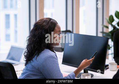 Seitenansicht einer jungen Geschäftsfrau, die im Büro telefoniert Stockfoto