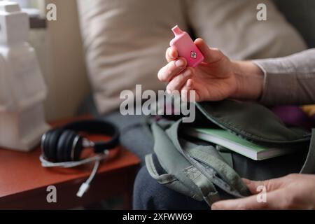 Mann, der elektronische Zigarette in der Hand hält, während er auf dem Bett sitzt Stockfoto