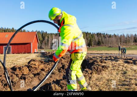 Wartungstechniker, der Kabel an sonnigen Tagen installiert Stockfoto
