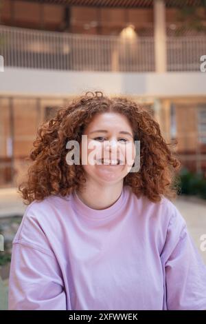 Porträt einer jungen Geschäftsfrau mit lockigem Haar, die im Büro lächelt Stockfoto