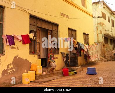 Junge, der sein Haus verlässt, wo Wäsche auf der Straße zu trocknen ist, beiderseits der Eingangstür Stockfoto