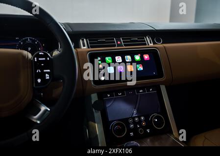 Innenraum mit Lederbesatz bei Nacht, Nahaufnahme des Infotainment-Systems. Apple CarPlay Hauptmenü im Executive Car. Stockfoto