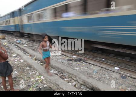 Ein Kind springt mit dem Seil, als ein Zug an ihr vorbeifährt, auf dem Karwan Basar, da die schienenbedingten Todesopfer zunehmen, da mehr als 80 Prozent der Bahnübergänge, au, überquert werden Stockfoto