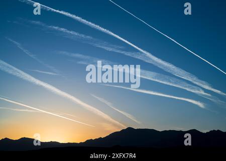 Funeral Mountains mit Kondensstreifen aus dem Flugzeugverkehr, die bei Sonnenaufgang den Himmel streiften. Death Valley National Park, Mojave Desert, Kalifornien, USA, April. Stockfoto