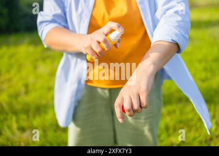 Mückenschutz. Frau benutzt Insektenspray draußen im Sommerpark. Stockfoto