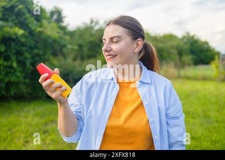 Mückenschutz. Frau benutzt Insektenspray draußen im Sommerpark. Stockfoto