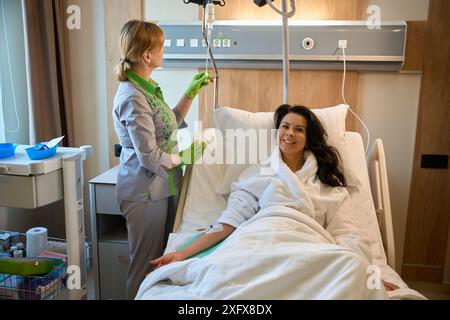 Die Krankenschwester in Uniform bringt einer Frau eine IV Stockfoto