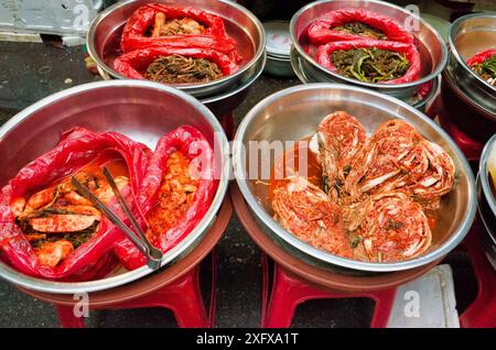 Lebhaftes koreanisches Street Food: Kimchi und andere fermentierte Gerichte in Metallschalen, die traditionelle kulinarische Kultur zeigen. Stockfoto