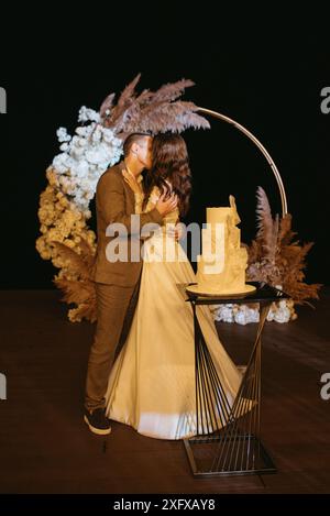 Frisch Vermählte schneiden, lachen und probieren die Hochzeitstorte Stockfoto