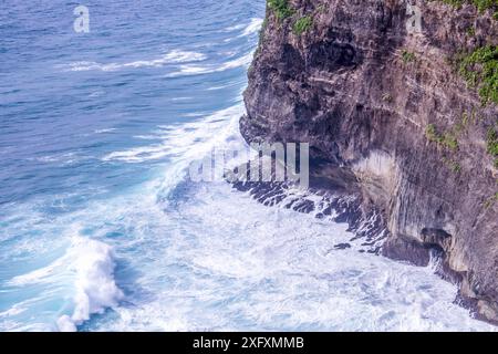 Die Wellen brechen gegen die zerklüftete Felsklippe am Meer in Uluwatu, Bali Stockfoto