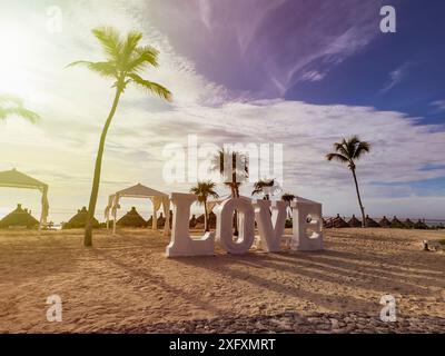 Romantisches Schild mit dem Wort Liebe an einem Strand aus goldenem Sand und sonnigem Himmel an der karibischen Sonne, in einer typischen tropischen und karibischen Umgebung, ideal für Stockfoto