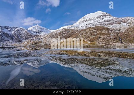 Crib Goch und Mount Snowdon spiegeln sich in teilweise gefrorenem Llyn Llydaw wider. Snowdonia-Nationalpark, Gwynedd, Nordwales, Großbritannien. März 2018. Stockfoto