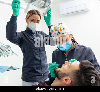 Eine Zahnärztin untersucht einen männlichen Patienten in einer Zahnarztpraxis mit professionellen Werkzeugen und persönlicher Schutzausrüstung. Stockfoto