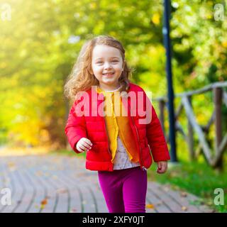 Adorable kleine Mädchen walking im Park auf einen Tag fallen. Weibliche Toddler mit gelb, rot und lila Kleidung. Stockfoto