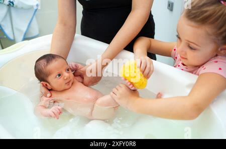 Erstes Bad des neugeborenen Jungen.die Mutter wäscht das Baby mit natürlichem Schwamm. Stockfoto