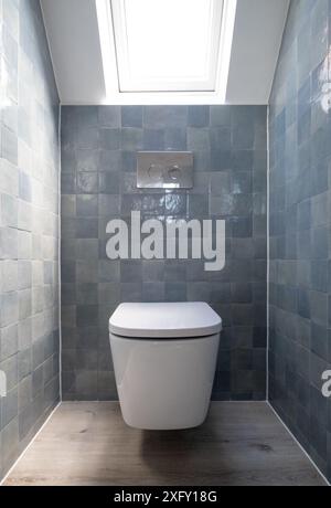 Kleine Toilette in Loft-Umbau mit cleverem Gebrauch der Traufe auf dem Dachboden. Architekt entworfen mit blauen Porzellan zellige Fliesen, weiße Wand hängende Toilette. Stockfoto