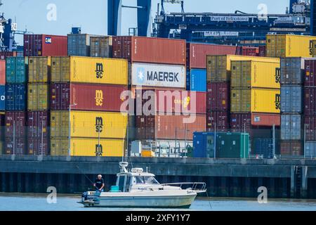 Mann fischt am Dock. Welthandel, Importe und Exporte. Versandcontainer gestapelt auf dem Dock in Felixstowe, River Orwell, Suffolk, England, Großbritannien Stockfoto