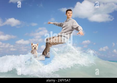 Männlicher Teenager mit einem Hund, der auf einer Welle im Meer surft Stockfoto