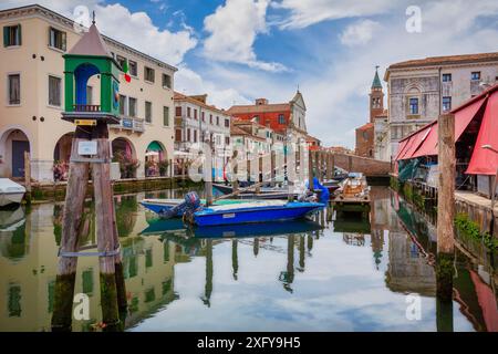 Die Kanalvene mit verankerten Booten und mit der Struktur des roten Fischmarktes, Chioggia, Gemeinde der Metropolstadt Venedig, Veneto, Italien Stockfoto