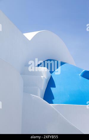 Traditionelle Architektur der Kykladen-Inseln, einer weiß getünchten Kirche mit abstrakten Kurven und der typischen blauen Kuppel, auf der Insel Therasia, Griechenland. Stockfoto