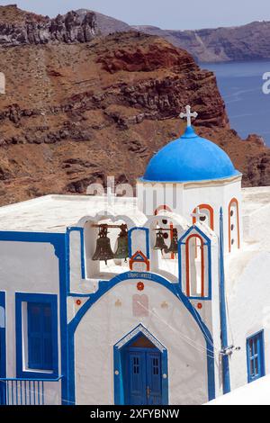 Griechische orthodoxe Kirche mit blauer Kuppel und weiß getünchtem Stil, vor dem dunklen, vulkanischen Boden der Insel Therasia in Griechenland und der berühmten Caldera Stockfoto