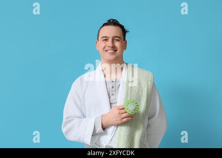 Junger Mann mit Haarkopfmassagegerät auf blauem Hintergrund Stockfoto