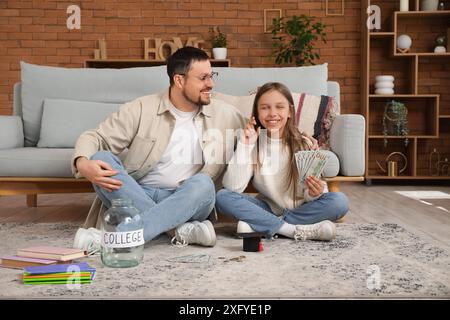 Vater und seine Tochter mit Glas, Mörserplatte und Geld zu Hause. Studiengebühren-Konzept Stockfoto