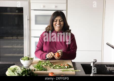 Fröhliche indische Küchenfrau, die gesunde Mahlzeit aus Bio-Lebensmitteln zubereitete Stockfoto