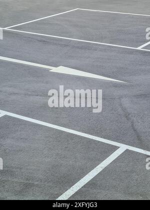 Ein Parkplatz mit weißen Markierungen für die Parkbuchten und weißen Pfeilen für die Fahrtrichtung, Parkordnung in Nordrhein-Westfalen Stockfoto