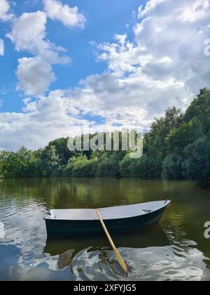 Ein leeres Kanu schwimmt allein auf dem See, Wolken bilden sich an einem Sommertag im August in Nordrhein-Westfalen Stockfoto