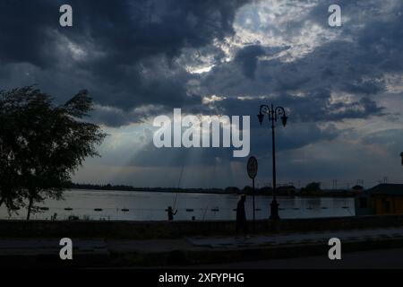 Srinagar, Jammu Und Kaschmir, Indien. Juli 2024. Ein Fußgänger spaziert am Ufer des Dal Sees entlang, nachdem Wolken den Himmel in Srinagar bedecken. Kaschmir kämpft mit einer seltenen Hitzewelle, bei der die Tagestemperaturen um sechs Grad über dem Normalwert liegen. Das Meteorologische (MET) Department hat jedoch für Teile von J&K Duschen vorhergesagt, die in den nächsten 24 Stunden wahrscheinlich etwas Erleichterung bringen werden. (Credit Image: © Adil Abass/ZUMA Press Wire/Alamy Live News) NUR REDAKTIONELLE VERWENDUNG! Nicht für kommerzielle ZWECKE! Stockfoto