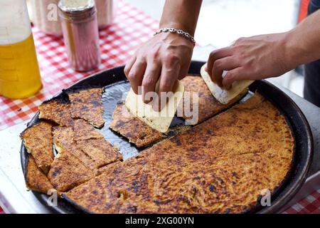 Socca, die gerade aus dem Ofen kommt, in Nizza, an der französischen Riviera. Socca ist eine Art dünner Socca, eine Spezialität der südöstlichen französischen Küche. Ein Pfannkuchen gemacht Stockfoto