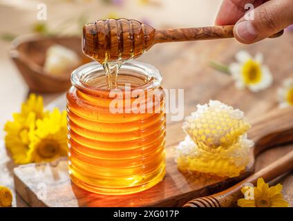 Natürlicher Bio-Honig im Glasgefäß, Honiglöffel und Waben sind in der Nähe. Natürlicher Lebensmittelhintergrund. Stockfoto