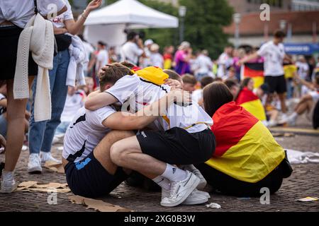Zwei deutschland Fans sitzen niedergeschlagen am Boden und umarmen sich gegenseitig. Fans der deutschen Nationalmannschaft liegen in Traenen nach dem Spiel gegen Spanien und dem Ausscheiden aus der EURO2024 beim Fanfest mit Public Viewing auf dem Stuttgarter Schlossplatz. Foto: Eibner-Pressefoto/Dennis Duddek Stockfoto