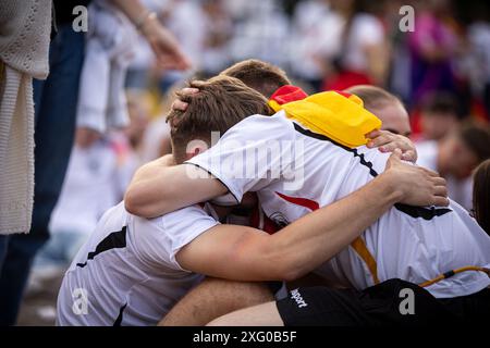 Zwei deutschland Fans sitzen niedergeschlagen am Boden und umarmen sich gegenseitig. Fans der deutschen Nationalmannschaft liegen in Traenen nach dem Spiel gegen Spanien und dem Ausscheiden aus der EURO2024 beim Fanfest mit Public Viewing auf dem Stuttgarter Schlossplatz. Foto: Eibner-Pressefoto/Dennis Duddek Stockfoto