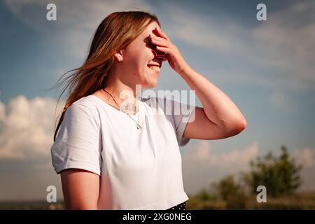 Eine Frau steht auf einem Feld und schirmt ihre Augen vor der Sonne ab. Stockfoto