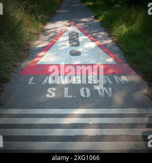 Eine Bitte, langsam auf Deutsch und Englisch auf einer schmalen Asphaltstraße zu fahren Stockfoto