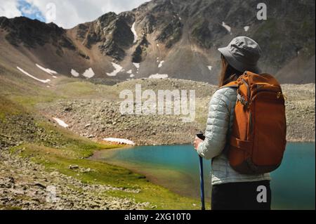 Blick von hinten, eine Touristenfrau steht mit Rucksack und Stöcke in panama unter der Sonne, blickt auf den See und die Berge im Sommer Stockfoto